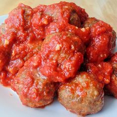 meatballs covered in marinara sauce on a white plate