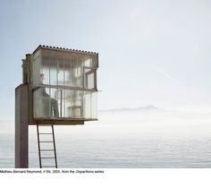 a lifeguard tower sitting on top of a beach next to the ocean in black and white