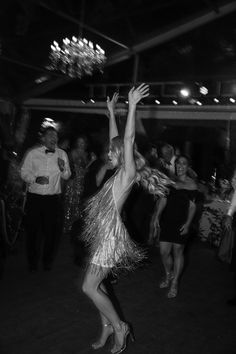 a woman is dancing on the dance floor with her arms in the air as people watch