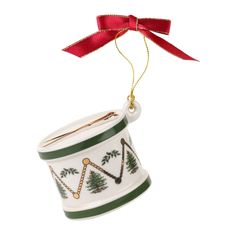 a christmas bell ornament hanging from a red ribbon on a white background with green trim