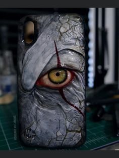 a cell phone case with an evil looking eye on the front and back cover that has been painted onto