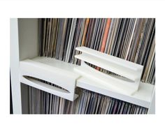 two white shelves holding records in front of a wall full of vinyl record's