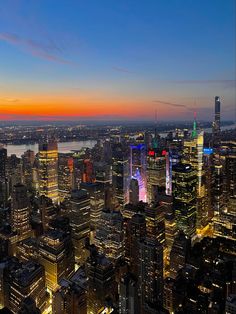 an aerial view of the new york city skyline at night with lights on and skyscrapers lit up