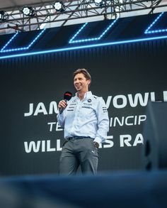 a man standing on top of a stage holding a microphone