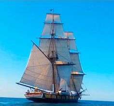 a large sailboat sailing on the ocean with blue skies in the backgroud