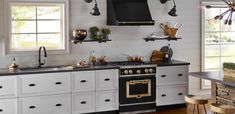 a kitchen with white cabinets and black counter tops is pictured in this image, there are several hanging lights above the stove