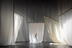 a woman standing in front of white curtains