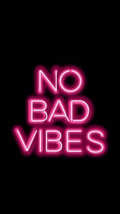 the words no bad vibes are lit up in pink neon letters on a black background