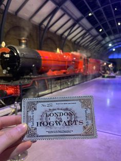 a ticket for hogwarts is held up in front of a train at the museum