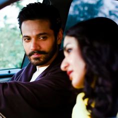 a man and woman sitting in the back seat of a car