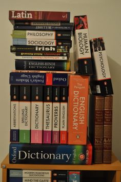 a stack of books sitting on top of a wooden shelf