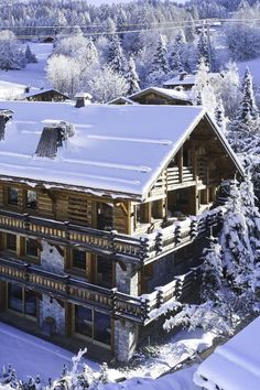 an aerial view of a large wooden house in the mountains covered with snow and trees