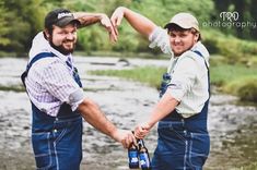 two men in overalls holding hands over a river