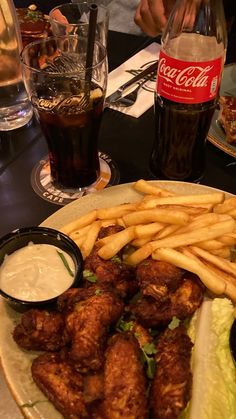 chicken wings and french fries on a plate with coleslaw, ketchup, and soda