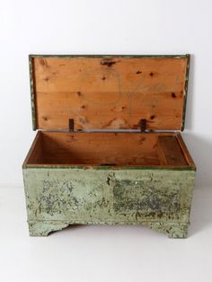 an old wooden box with graffiti on it's lid sitting on a white surface