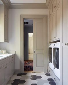 a white washer and dryer sitting in a kitchen next to a sink on top of a checkered floor