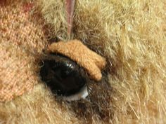 a stuffed animal with a brown hat on it's head is seen through the hole in the fur