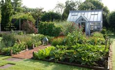 a garden filled with lots of different types of flowers and plants next to a building