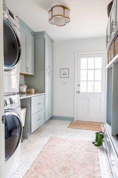 a washer and dryer are in the middle of a room with light blue cabinets