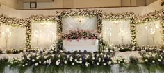 a white wedding cake sitting on top of a table covered in flowers and greenery