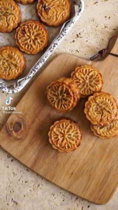 several small pastries on a cutting board next to a tray with other pastries