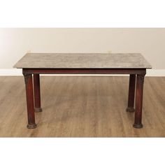 a marble top table with wooden legs on hardwood flooring in front of a white wall