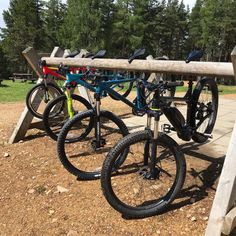 two bikes are parked next to each other on a bench at a park with trees in the background