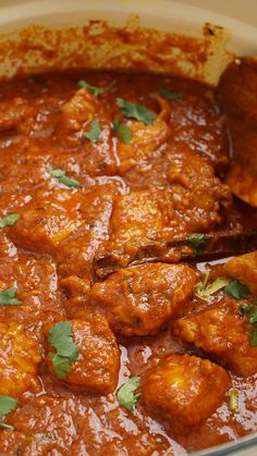 a large pot filled with meat covered in sauce and garnished with cilantro