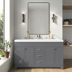 a bathroom vanity with two sinks and a large mirror above it, in front of a window