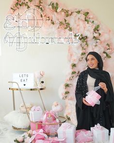 a woman standing in front of pink presents