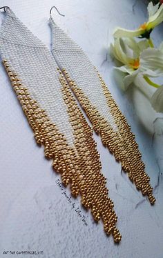 two pairs of gold and white beaded chandelier earrings on top of a table