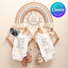 two baby onesuits hanging on a wall next to a rainbow shaped photo frame