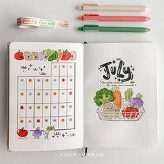 an open planner with fruits and vegetables on it next to markers, pens and markers