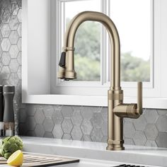 a kitchen faucet that is in front of a window with some fruit on the counter