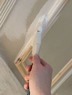 a person using a brush to paint a ceiling