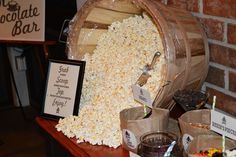 a wooden barrel filled with popcorn sitting on top of a table next to other items