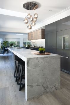 a modern kitchen with marble counter tops and stainless steel appliances, along with bar stools