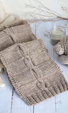 a knitted scarf sitting on top of a table next to yarn and a knitting needle