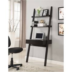 a desk with a laptop on top of it next to a chair and wall hangings