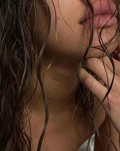 a close up of a woman with wet hair on her face and hands in front of her face