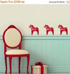 a red chair sitting in front of a wall with three horse decals on it