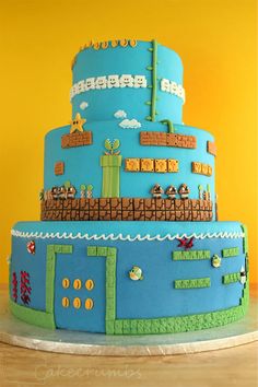 a blue cake with video game characters on it's sides and the top tier is made out of fondant