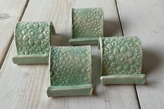 four pieces of green pottery sitting on top of a wooden floor