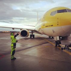 a man standing in front of an airplane on the tarmac, pointing at it