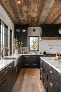 a kitchen with black cabinets and wood floors, along with white counter tops that match the wooden ceiling