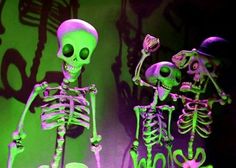 two skeleton figurines are standing next to each other in front of a green background