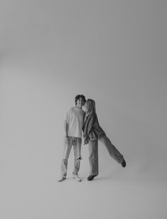 two people standing in the middle of a white room with their arms around each other