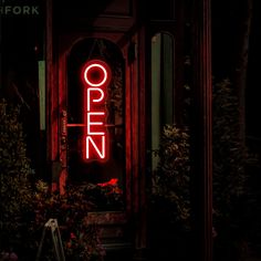 the open sign is lit up in front of an entrance to a restaurant at night