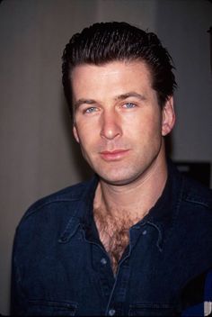 a close up of a person wearing a denim shirt and looking at the camera with a serious look on his face