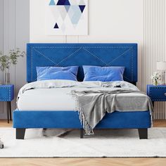 a bed with blue upholstered headboard and foot board in a white room